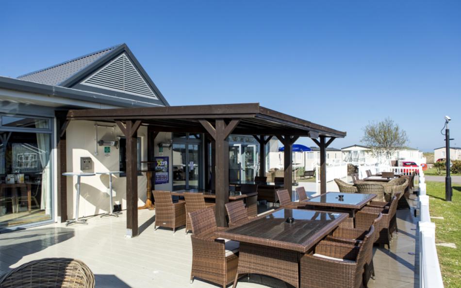 A Bar and Outdoor Seating Area with Tables and Chairs Surrounded by Lodges