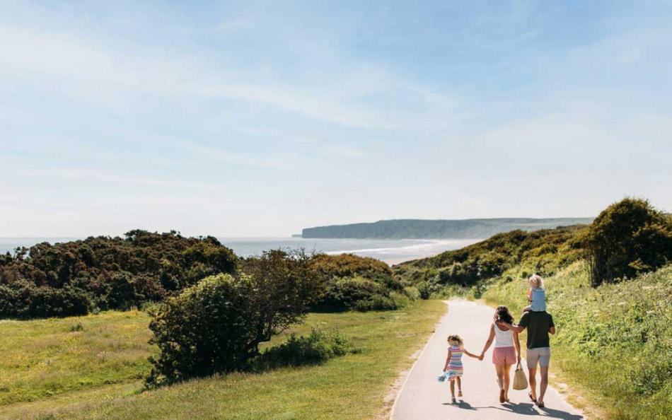 People walking along a path down towards the Sea